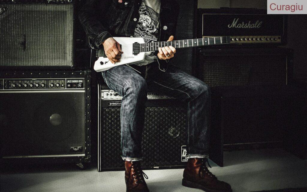 Man Sitting on Guitar Amplifier Playing Electric Guitar