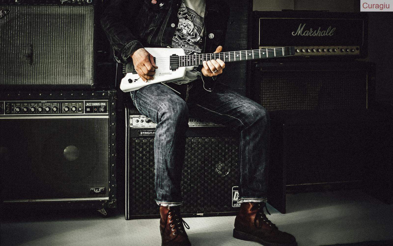 Man Sitting on Guitar Amplifier Playing Electric Guitar