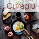 Top view of fried eggs with mint in pan near fruits and bread on wooden table