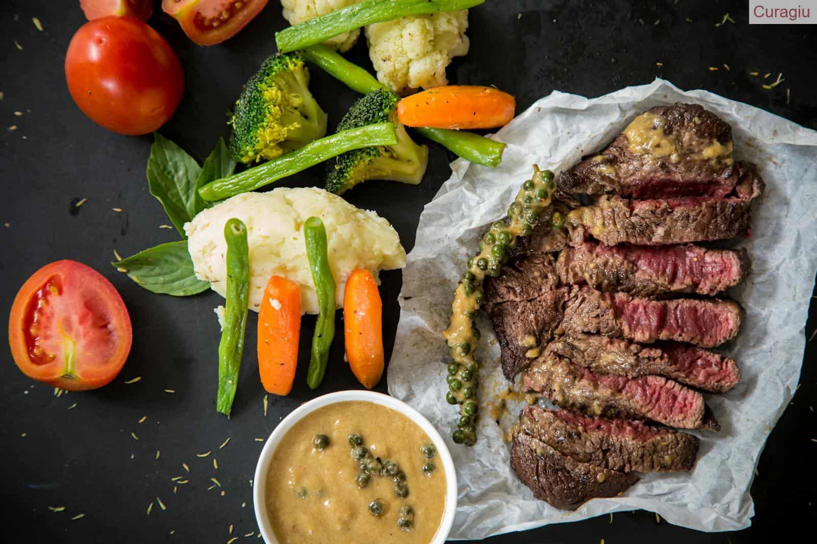 Grilled steak served with fresh vegetables and pepper sauce, presenting a colorful and appetizing meal.