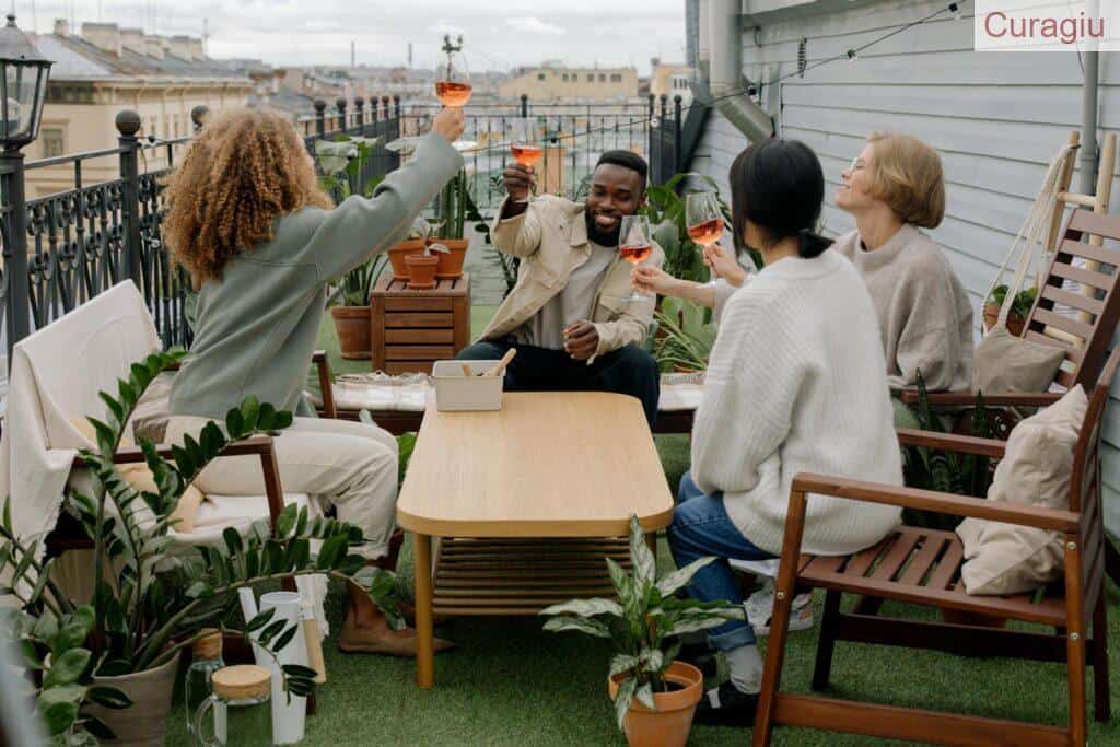 Four friends enjoying a wine toast on a cozy outdoor veranda with potted plants.